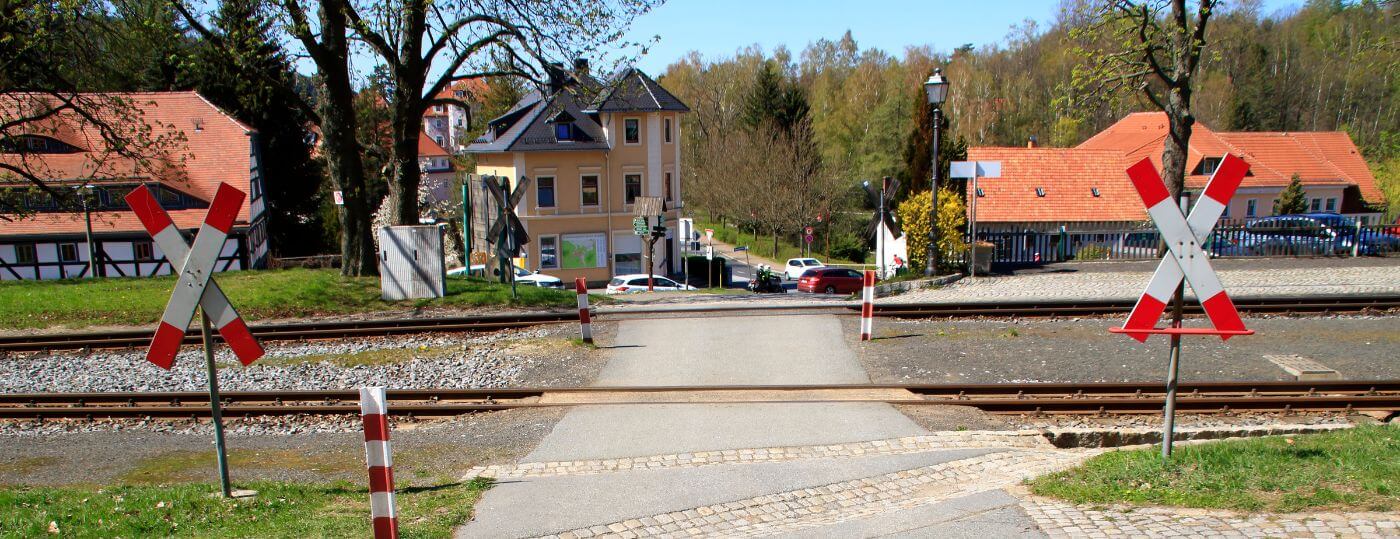 Bahnübergang mit Andreaskreuzen in einer deutschen Kleinstadt Bahnübergang mit zwei Andreaskreuzen und Bahngleisen in einer ländlichen Ortschaft mit Fachwerkhäusern im Hintergrund.