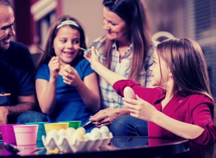 Familie bemalt Ostereier und sich gegenseitig.
